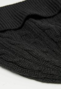 Černá pletená čepice s ribbed texturou a vzorem s kabelkovým pletením, s ohrnutým lemem pro přidané teplo a styl.