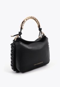 Bolso de cuero negro con laterales trenzados, asa de metal dorada grabada con "Lola Casademunt," y logo dorado a juego en la parte delantera.