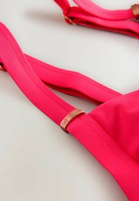 Fuchsia-Bikini-Oberteil mit breiten, glatten Trägern und einem eingearbeiteten Rosegoldenen Metallversteller. Strukturierter Stoff und nahtloses Design.