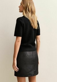 Zwarte wolblend korte mouwen trui met een fitted silhouet, gecombineerd met een zwarte textuur nepleer minirok.