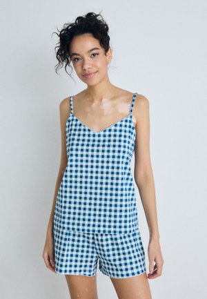 Sininen ja valkoinen ruudullinen pyjama-asuste, joka on valmistettu kevyestä kankaasta ja jossa on v-aukkoinen yläosa, jossa on ohuet hihnat, sekä yhteensopivat shortsit.
