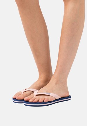 Chanclas de goma rosas con suela azul marino. Presentan una correa texturizada y un diseño de suela en capas con rayas horizontales blancas.