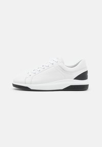 Baskets en cuir blanc avec une texture lisse, semelle en caoutchouc noir et accents gris au talon. Comprend six œillets et des lacets plats.