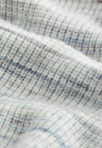 Tissu en laine tricoté de couleur gris clair avec des rayures bleues. Apparence douce, texturée et duveteuse avec des motifs horizontaux.
