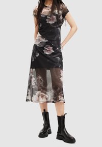 Black floral midi dress with sheer sleeves and a layered design. Features a mix of roses and patterns. Paired with chunky black ankle boots.