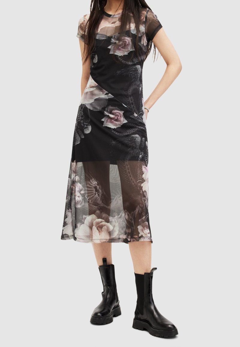 Black floral midi dress with sheer sleeves and a layered design. Features a mix of roses and patterns. Paired with chunky black ankle boots.