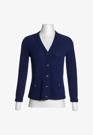 Cardigan tricoté bleu marine à manches longues, cinq boutons devant, deux petites poches avant et col en V sur un mannequin.
