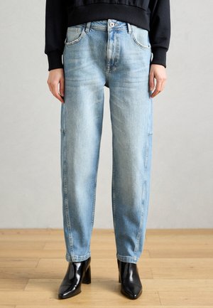 Lys blå denimjeans med en avslappet passform, med glidelås, fem lommer og subtil fading, paret med svarte hæl sko.