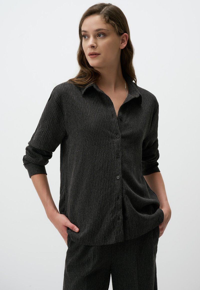 Zwarte textuur knoopshirt met een kraag en lange mouwen opgerold bij de manchetten, met verticale strepen en een relaxte pasvorm.