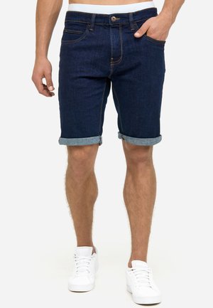 Shorts din denim albastru cu margini răsucite, design cu cinci buzunare și cusături în contrast. Purtați cu adidași albi pentru un look casual.