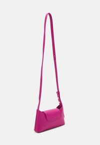 Piccola borsa a tracolla in pelle rosa brillante, con lungo strap regolabile e chiusura a patta, su sfondo bianco.