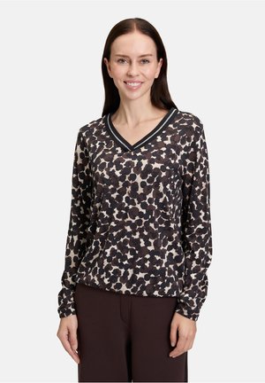 Top a maniche lunghe con scollo a V in un motivo leopardato, caratterizzato da una combinazione di colori in bianco e nero, con un tessuto testurizzato e rifiniture a contrasto.
