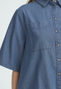 Kurzarm-Denimhemd in Dunkelblau, mit Knopfverschluss, einer Brusttasche und einer leicht lockeren Passform mit glatter Textur.