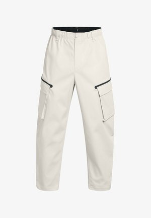 Bežové cargo nohavice vyrobené z hladkej tkaniny, s elastickým pásom, dvoma bočnými vreckami a čiernymi ozdobnými detailmi.