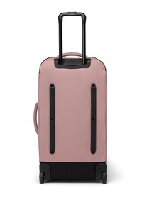 Skládací kufr v světle růžové tkanině, vybavený sklopným černým madlem, dvěma černými popruhy a černým spodkem s kolečky.
