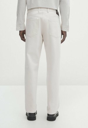 White denim pants with a straight-leg cut, featuring two back pockets and a smooth texture, paired with black shoes.