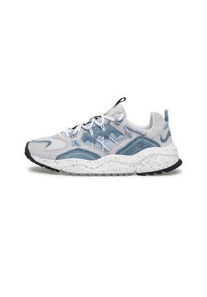 Lichtgrijze en blauwe sportieve sneaker met een dikke witte zool met spikkels, een zwarte zoolprofiel, lussen om aan te trekken en witte veters met meerdere oogjes.
