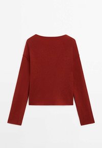 Pull court rouge à manches longues, confectionné en maille texturée. Il présente un col large et une coupe décontractée.