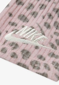 Rožinė medžiaga su raukšlėta tekstūra, kurioje yra pilkų leopardų dėmių. Priedo yra siuvinėtas baltas "Nike" logotipas.