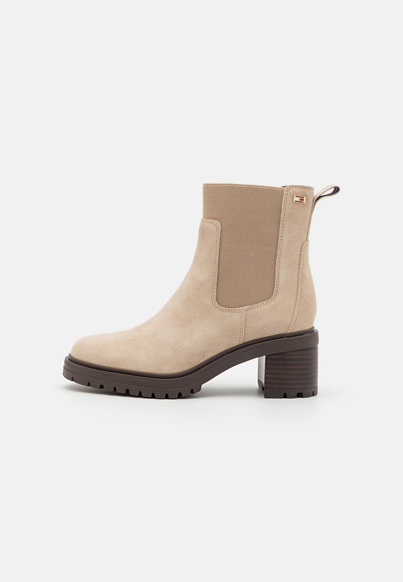 Bottine en suède beige avec des panneaux latéraux élastiques, un bout rond et un talon carré marron texturé. Dotée d'une languette à l'arrière.