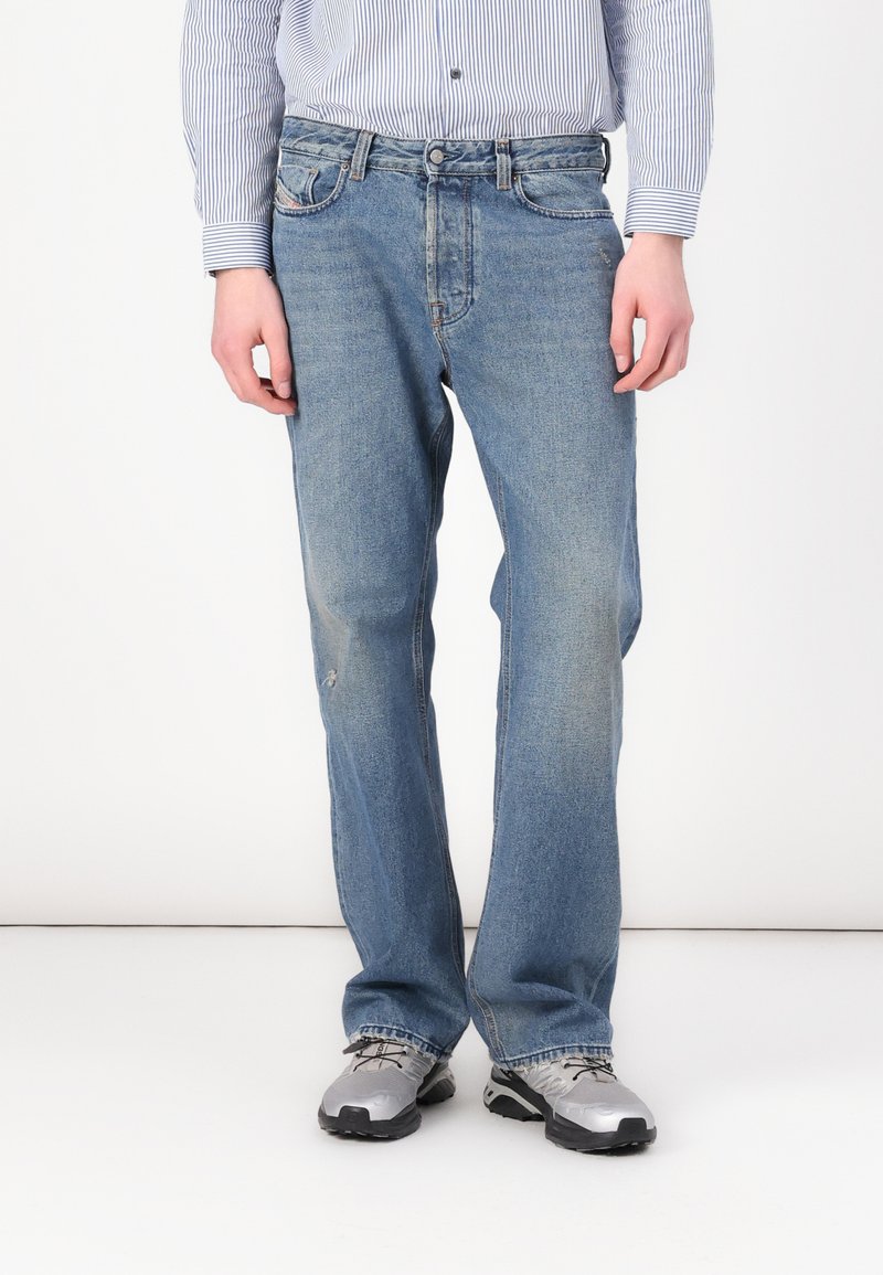 Light blue, straight-leg denim jeans with faded sections and minor fraying. Paired with gray athletic shoes.