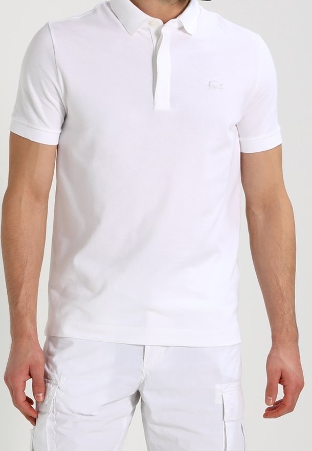 Polo shirt blanc à manches courtes en coton. Il présente un col plat, une patte de boutonnage à trois boutons, un logo subtil sur la poitrine et une texture lisse.