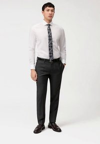 White dress shirt, patterned dark tie, dark tailored trousers, black belt, and dark loafers. Smooth fabric, polished look, fitted design.