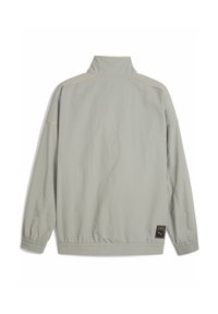 Lys grå jakke med høj krave, elastiske manchetter og kant. Har gule stikninger og et logo patch på venstre side. Struktureret stof.