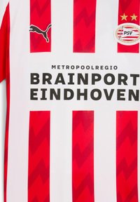 Röd och vitrandig fotbollströja med Puma-logotyp, PSV Eindhoven-emblem och sponsortexten Brainport Eindhoven.