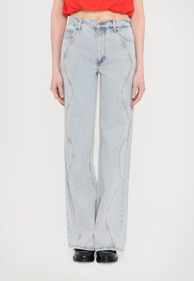 Jeans din denim de un albastru deschis, cu croială largă și ornamente argintii ondulate pe marginile laterale. Dispune de cinci buzunare și închidere cu nasture.