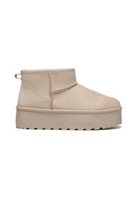Botines beige de ante suave, con punta redondeada, acentos en las costuras laterales, una tira para facilitar el calzado y una suela de plataforma gruesa con textura estriada.