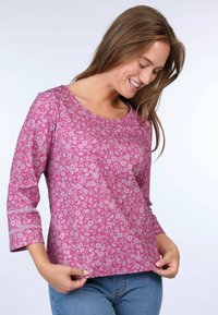 Pink floral print top with three-quarter length sleeves, round neckline, and a relaxed fit. Features a soft texture and subtle accent stitching.