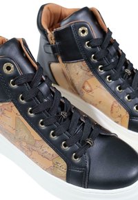 Sneaker alte nere con un lato in pelle marrone a motivo mappa, occhielli dorati e lacci neri. La suola è bianca e testurizzata.