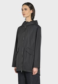 Giacca nera con cappuccio realizzata in materiale leggero e impermeabile. Presenta una zip frontale, due tasche anteriori e una vestibilità comoda.