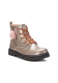 Botín dorado brillante con pom-pom rosa y detalle de mariposa, que cuenta con cordones de satén marrón y una suela negra texturizada.