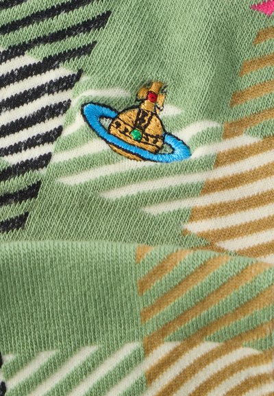 Πλεκτό ύφασμα με πράσινο φόντο και μπεζ, λευκές και μαύρες ρίγες. Φαίνεται ένα κεντημένο χρυσό καμπανάκι με μπλε και πράσινες λεπτομέρειες.