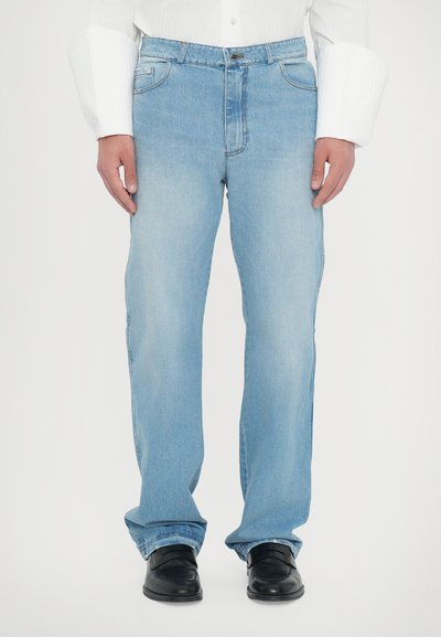 Jeans de culoare albastru deschis, cu un design drept al piciorului, stil clasic cu cinci buzunare și o ușoară decolorare, asortați cu pantofi negri.