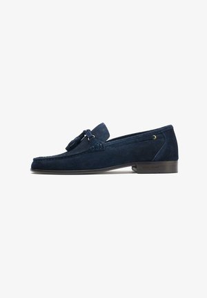 Navy blue suede loafers featuring a tassel accent, rounded toe, and a low wooden heel, with stitched detailing along the edges.