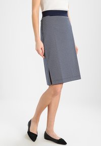 Navy ja valge triibuline pliiatsiseeliku, millel on slim-fit, keskmine pikkus ja külgslit, et võimaldada mugavat liikumist. Sile ja veniv kangas koos kindla vöökohaga.
