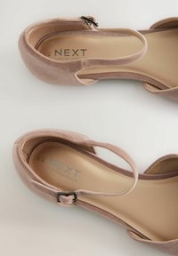 Helle rosa Wildlederabsätze mit einem Knöchelriemen, runder Zehenpartie und Schnallendetail. Das Innere zeigt die Marke "NEXT FOREVER COMFORT". Glatte Textur.