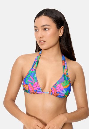 Mujer con cabello largo y oscuro, usando un bikini tipo halter con estampado floral colorido, mirando hacia su derecha sobre un fondo liso.