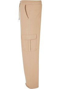 Beige svettbyxor med dragsko i midjan, sidofickor och en cargoficka på låret. Tillverkade av mjukt, texturerat material.