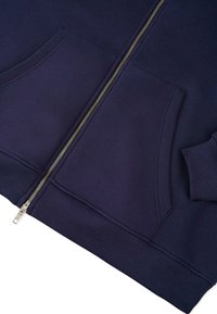 Felpa zip con cappuccio di colore blu scuro, dotata di due tasche frontali, polsini e orlo a coste. La cerniera è di colore argento, in contrasto con il tessuto.
