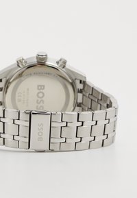 Orologio da polso cronografo in acciaio inox con finitura lucida, dotato di bracciale in maglia argento e cassa rotonda con branding inciso.