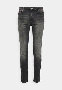Jeans ajustados en denim de lavado oscuro con un acabado desgastado. Cuenta con un diseño clásico de cinco bolsillos y herrajes metálicos en la cintura.