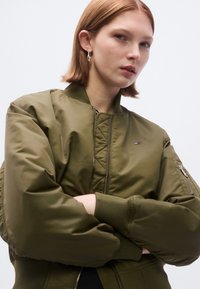 Χακί πράσινο μπουφάν bomber με ριμπ μανσέτες και γιακά. Διαθέτει φερμουάρ στο κέντρο και πλαϊνές τσέπες. Περιλαμβάνει μικρό λογότυπο στο στήθος.