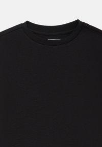 Must musträpped T-särk, mis on valmistatud pehmest kangast, kus on sile tekstuur ja õlavarre äärtes diskreetne õmblusdetail.