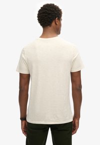 Crème kleurig katoenen T-shirt met een ronde halslijn en korte mouwen, gezien vanuit de achterkant. Zachte textuur en een ontspannen pasvorm.