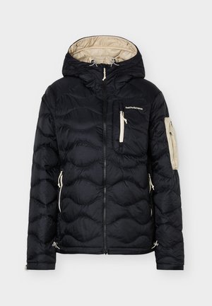 Sort quiltet hættejakke med beige for, lynlåslommer foran og på ærmerne samt "Peak Performance"-logo på brystlommen.