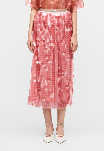 Jupe midi rose en tissu transparent, décorée de sequins circulaires superposés. Taille élastique avec un léger éclat, design en couches.